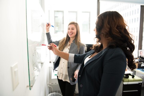 Two girls writing on a whiteboard